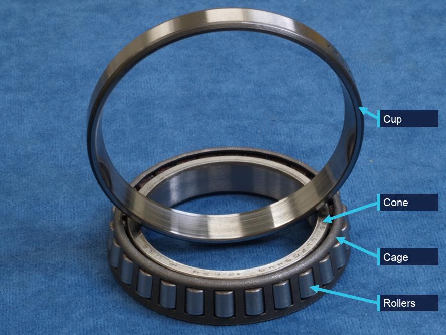 Tapered roller bearing cone and separate outer cup on a clean industrial surface Tapered roller bearing cone and separate outer cup on a clean industrial surface
